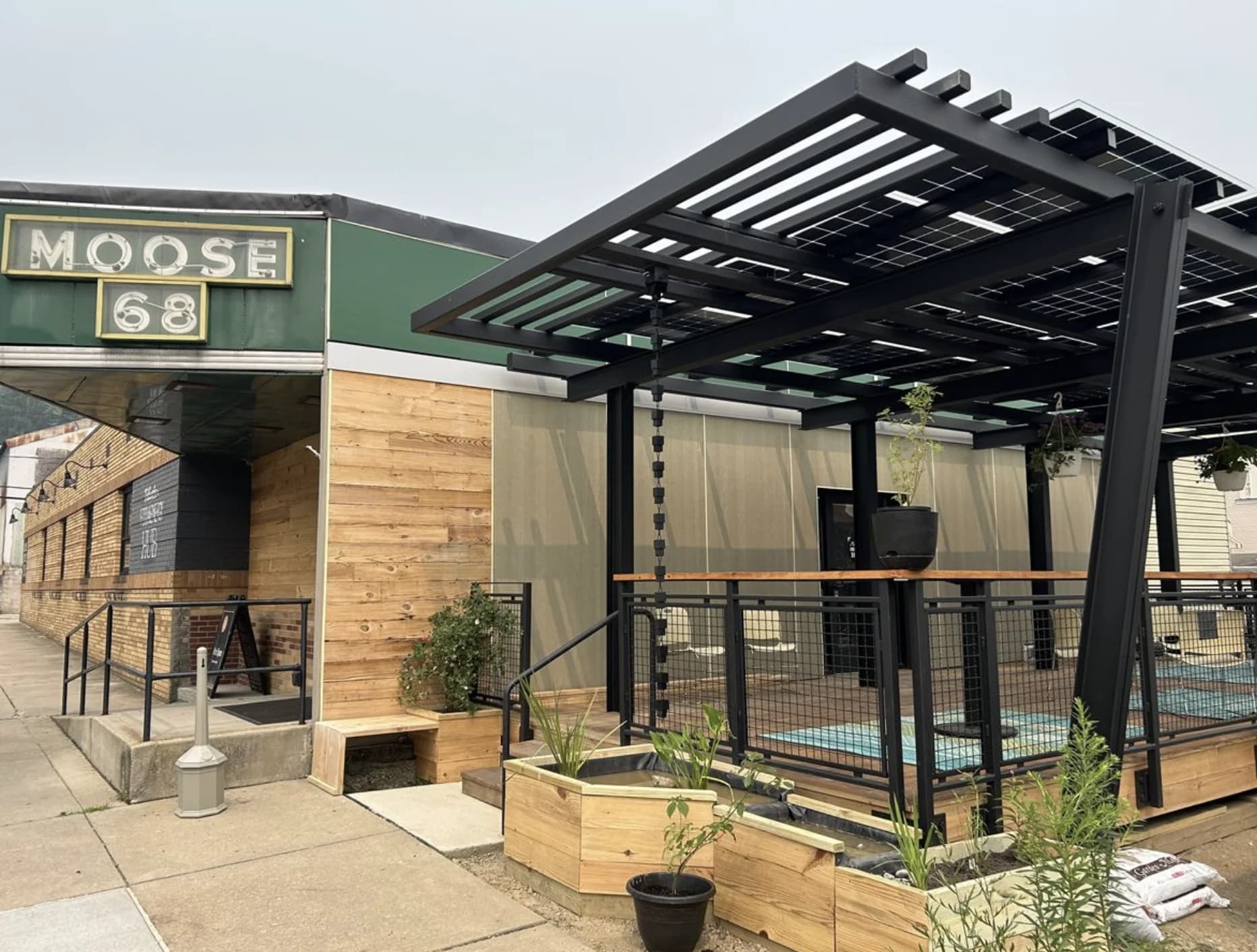 Moose 68, a community gathering space with a cedar facade and a solar canopy over its street-side patio